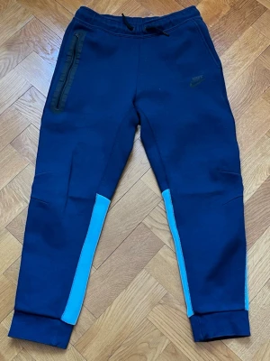 Två färgade Nike tech byxor - Nike tech byxor size 147-158. Dessa hör till samma set som den andra tech fleecen som jag har lagt upp, jag kan tänka mig att sänka priset om du köper dessa två tillsammans.