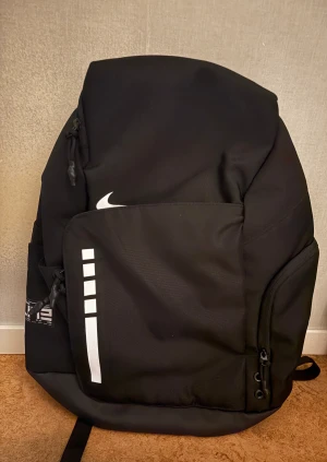 Svart Nike Elite ryggsäck - Nike Elite ryggsäck i svart med vita detaljer och logga. Snygg, sportig design med flera fack.