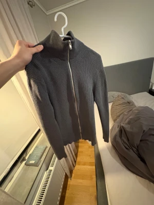  East west Mörkgrå stickad cardigan jacka. - Skit fet extremt grisch cardigan/hoodie. Riktigt bra skick har inga tecken på användning. Perfekt slim fit passform. Skriv direkt om du har frågor eller vill ha bild när jag har på den för att se hur den sitter. Jag är 186 och den passar mig perfekt