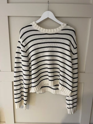 Randig stickad tröja i vitt och svart - Säljer en snygg stickad tröja med vita och svarta ränder. Tröjan har en avslappnad passform, ribbade muddar och rund halsringning. Perfekt för lager-på-lager och funkar året runt. Klassisk och enkel stil som alltid är rätt. (Står att den är L men passar som en S/M) 