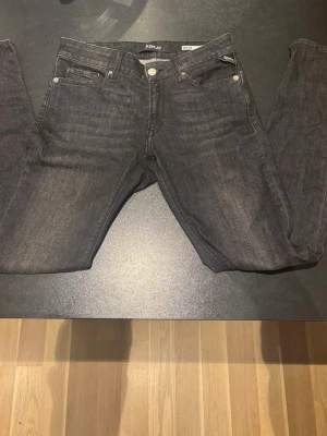 Replay New Luz svarta jeans 27/30 - Snygga svarta jeans från Replay, modell New Luz. Klassisk femficksdesign med silverfärgade nitar och knapp, samt Replay-logga på fickan. Jeansen har en rak passform och är tillverkade i mjukt denim-material som sitter skönt hela dagen. Storlek 27/30
