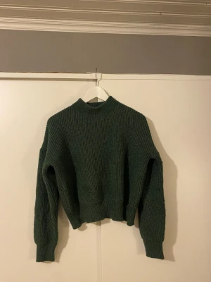 Grön stickad tröja - M Tröjan har en ribbad struktur, lite högre hals och stretchigare