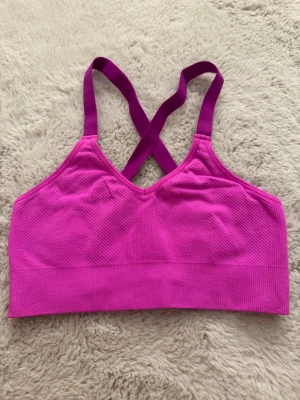 Rosa sporttopp  - Säljer en rosa sporttopp från H&M Sport i storlek 158/164. Toppen har ribbad struktur, korsade axelband i ryggen och är tillverkad i stretchigt material som passar perfekt för träning. Aldrig använd!!!!  
