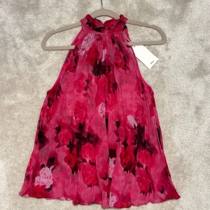Blommig rosa halterneck blus från MNG - Halterneck topp från mango. Helt oanvänd med prislapp på🩷den är genomskilnig och i storlek xs. 