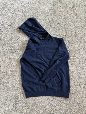 Mörkblå hoodie från JAJA - Mörkblå hoodie från JAJA med klassisk huva och långärmad design. Tröjan är tillverkad i en mjuk mix av bomull, ull och spandex som gör den både bekväm och flexibel. Perfekt för chill dagar och enkel att matcha med jeans eller joggers. Snören till luvan följer med. Skickas inom 24h efter köp. Hör av dig vid frågor. 📦🚚❤️