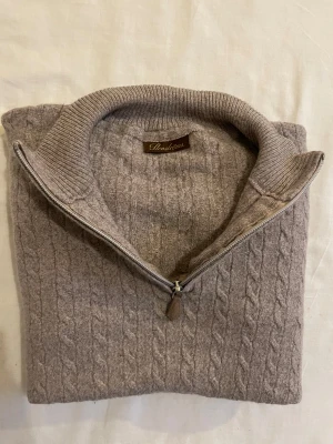 Beige kabelstickad half zip från Stenströms - Snygg beige kabelstickad tröja från Stenströms med half zip och ribbad krage. Tröjan har ett klassiskt mönster och är tillverkad i mjuk ull, perfekt för kyliga dagar. Passar dig som gillar stilren och tidlös design.