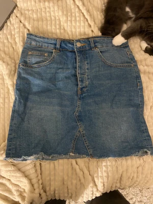 Blå jeanskjol från Gina tricot - Snygg blå jeanskjol från Gina. Passformen är inte strl 40 jag skulle säga 38 och materialet är bomull. Perfekt för dig som gillar en chill och trendig denimlook.