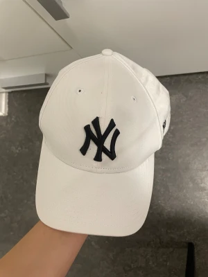 Vit New York Yankees keps 9FORTY - Snygg vit keps från New Era med klassiskt New York Yankees-logo broderat i svart framtill. Modellen är 9FORTY med böjd skärm och justerbart metallspänne bak. 