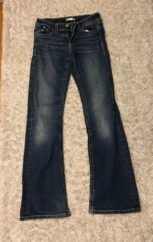 Blå bootcut jeans från Gina Tricot - Snygga blå jeans från Gina Tricot i storlek 158. Modellen har bootcut-ben, klassiska fickor med lock och knappar bak, samt slitningar vid benslut men har fortfarande en fin helhet💕💕De är tyvärr för små för mig så det är därför jag säljer. Det är bara att höra av dig om du vill diskutera pris❤️