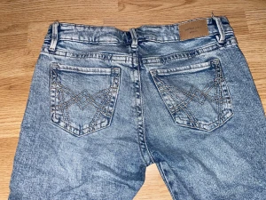Perfekt Jeans ljusblå bootcut - Priset går att diskuteras, Säljer ett par ljusblå bootcut jeans med snygga detaljerade sömmar på bakfickorna. Jeansen har klassisk femficksdesign och är tillverkade i jeansmaterial med en skön passform. Perfekt för dig som gillar retrovibbar och stilrena jeans. Köpt för 250kr