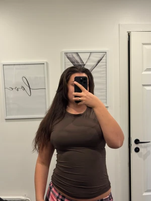 Brun tight t-shirt med kort ärm - Säljer en brun, tight och figurnära t-shirt med korta ärmar och rund halsringning. T-shirten är enkel och stilren, perfekt att matcha med jeans eller kjol. Materialet känns mjukt och stretchigt, vilket gör den riktigt bekväm att bära. L/XL men passar M med 