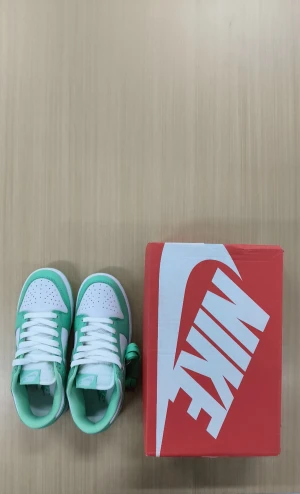 Nike Dunk Low Mintgrön/Vit - Nike Dunk Low sneakers i fräsch mintgrön och vit färg. Klassisk låg siluett med vit bas och mintgröna overlays, vit swoosh och matchande snörning. Skorna har en platt sula och kommer med extra mintgröna skosnören. Perfekta för dig som vill sticka ut med stil.