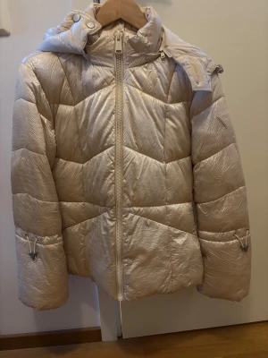 Guess vinterjacka - Snygg beige pufferjacka från Guess. Inte använd mycket. Köpt för 1800kr. Pris kan diskuteras. 
