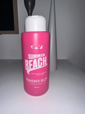 Summer Beach Shower Gel 400ml - Tropisk duschgel i en snygg rosa plastflaska med vit kork. Innehåller aloe vera och rosblomsextrakt för en fräsch känsla. Perfekt för dig som vill ha en somrig vibe i badrummet. Doften är inspirerad av tropiska stränder.