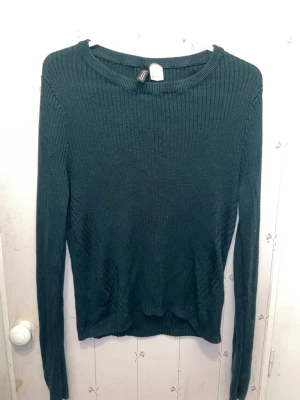 Mörkgrön ribbad tröja H&M Divided - Snygg mörkgrön långärmad tröja från H&M Divided i storlek L. Tröjan är ribbstickad med rund hals och har en slim passform. 