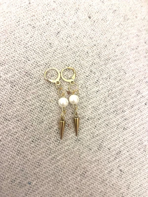 Guldiga örhängen med pärlor och spikes - Snygga örhängen med guldfärgade detaljer, vita pärlor och coola konformade spikes. Perfekt för dig som gillar att sticka ut med din stil och vill ha något unikt till öronen. Hängande modell med modern vibe.