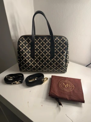By Malene Birger Moshie – designerväska inkl. dustbag - Säljer en elegant och stilren By Malene Birger Moshie-väska i mycket fint skick. Väskan är hel, välvårdad och utan skador. Det klassiska mönstret gör den tidlös och lätt att matcha till både vardag och mer uppklädda tillfällen.  Väskan kommer med: 	•	Två avtagbara band (ett kort och ett längre, justerbart) 	•	Original dustbag/påse  Kan bäras både i handen och crossbody beroende på band. Perfekt storlek för vardagsbruk – rymmer det viktigaste som mobil, plånbok och smink.  Nypris: 3200kr