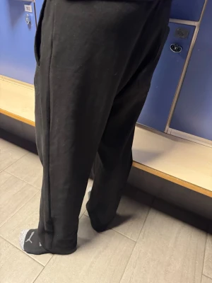 Svarta mjukisbyxor med fickor - Säljer ett par svarta mjukisbyxor med avslappnad passform och stora fickor på sidorna. Byxorna är tillverkade i mjukt bomullsmaterial och har en loose fit som gör dem riktigt sköna att ha på sig. Perfekta för chill eller träning.