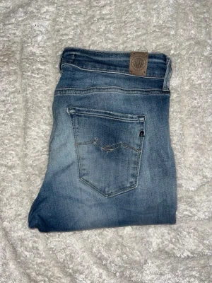 Replay jeans  - Säljer ett par blå Replay jeans. OBS jeansen har ett hål på ena knät. Midja 36cm, längd 99cm. JAG SKICKAR EJ FLER BILDER NÄR JAG BÄR JEANSEN! för bättre inblick i passformen rekommenderar jag att googla på modellnamnet. För storleksguide kolla måtten noggrant då jeansen alltid kan vara uppsydda heller krympta och jag ej tar emot returer :) s6,1