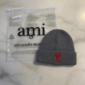 Grå ribbstickad mössa från Amiii - Stilren mössa med broderad hjärtlogga framtill. Klassisk ribbstickad modell som passar både till vardag och mer uppklädda outfits. Bekväm passform och tidlös design. Sparsamt använd och i mycket fint skick. 