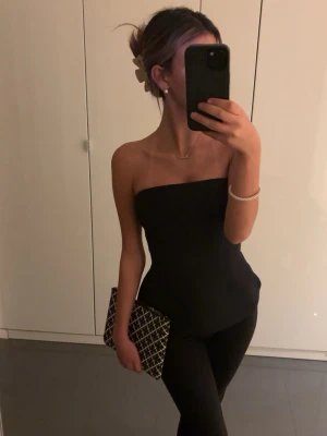 Svart axelbandslös tubtopp - Säljer en stilren svart tubtopp med axelbandslös design. 