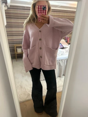 Ljusrosa oversized kofta med knappar - Supermysig ljusrosa kofta i oversized modell med stora fickor framtill och snygga knappar. Koftan är stickad och har långa ärmar samt ribbade muddar vid ärmslut och nederkant. Perfekt att slänga på sig när det är lite kyligt ute. H&m premium