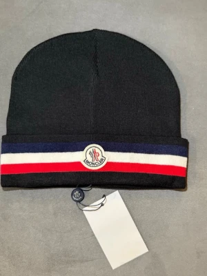 Moncler Mössa - Helt ny moncler mössa, riktig varm mössa med täcket huvud och öron. Perfekt till den kyliga vintern just nu, 1-3 dagars leveranstid, köp innan 20:00 och det skickas samma dag!