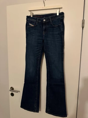 Mörkblå bootcut jeans från Diesel - Säljer ett par mörkblå jeans från Diesel i klassisk bootcut-modell. Jeansen har fem fickor, snygga kontrastsömmar och en liten Diesel-logga på fickan fram. Nypris 1800