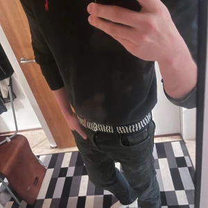 Svart stickad tröja från Polo Ralph Lauren - Klassisk svart stickad tröja från Polo Ralph Lauren med röd broderad logga på bröstet. Tröjan har rund halsringning och långa ärmar. Perfekt till jeans eller chinos för en clean och stilren look.