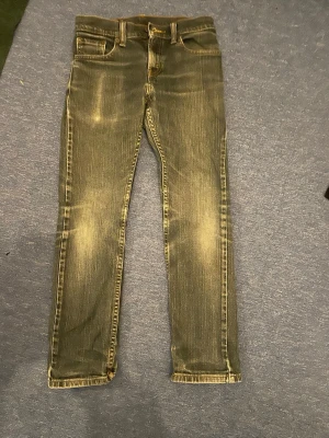 Levi's 511 Slim Fit jeans blå - Säljer ett par Levi's 511 Slim Fit jeans i blå tvätt med snygga slitningar. Klassisk femficksmodell med smal passform och normal midja. Tillverkade i 99% bomull och 1% elastan för lite stretch. Perfekta för dig som gillar en modern och clean look.