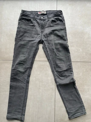 Grå Levi's 512 skinny jeans - Säljer ett par grå Levi's 512 skinny jeans med klassisk femficksdesign och smal passform. Jeansen har normal midja och är tillverkade i mjukt denimtyg som ger en bekväm känsla. Perfekta för dig som gillar en stilren och enkel look.