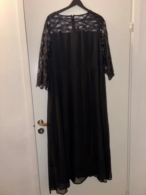 Svart långklänning med spetsdetaljer - Säljer en svart långklänning från Shein med transparenta spetsdetaljer upptill och på ärmarna. Klänningen har trekvartsärm och ett flowy fall. Materialet är polyester och spetsen har ett grafiskt mönster som ger en cool look.