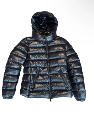 Svart Moncler pufferjacka med huva - Moncler Down jacket classic BADY model It can be worn in the city, in the mountains, super versatile. White goose down jacket of the finest quality. I listed it for sale as "good condition" even though it is in very good condition. In fact there is a mini scratch and a mini hole in the back that I posted a photo of, but it is barley visible.The down jacket was purchased on vestierie collective, but was originally purchased by the seller directly from moncler  Geneva Eur 945.00 Note that this cla