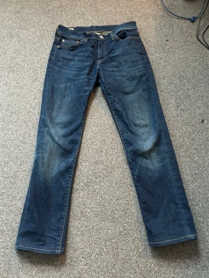 Levi's 511 mörkblå jeans W28 L32 - Säljer ett par Levi's 511 jeans i mörkblå tvätt. Klassisk femficksmodell med raka ben och snygga kontrastsömmar. Jeansen är tillverkade i slitstarkt denim och har den ikoniska läderpatchen bak i midjan. Perfekta för dig som gillar en tidlös och clean look. Kan diskutera pris.