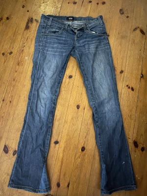 Blå bootcut jeans från Lee - Säljer ett par blå jeans från Lee med bootcut passform. Jeansen har snygga kontrastsömmar och Lee-logga på bakfickan. Köpt på vinted men är för små och har då ej använts. Står ej storlek men skulle uppskatta de som xs. 