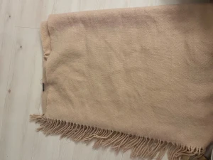 Beige/rosa  halsduk från Glitter - Stor och mjuk beige/rosa halsduk från Glitter med klassiska fransar längs kanterna. Halsduken har en enkel och stilren design i stickad material som gör den perfekt att svepa runt halsen när det är kyligt ute. Snygg att matcha med din favoritjacka.