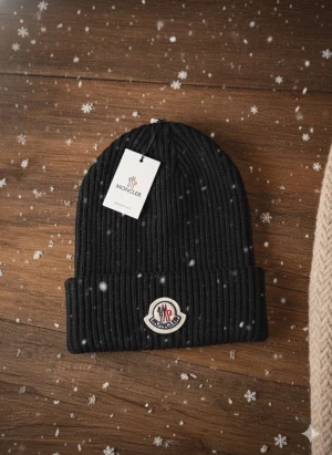 Svart Moncler mössa - Svart ribbstickad mössa från Moncler med klassisk uppvikt kant och broderad logotyp framtill. Riktigt bra nu till vintern, men även som julklapp