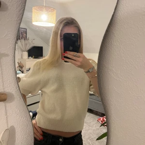 Krämvit stickad tröja med puffärm - Säljer en krämvit stickad tröja med korta puffärmar, Tröjan har en mjuk och lite fluffig yta som ger en mysig känsla. Passformen är normal och modellen är enkel men ändå trendig.