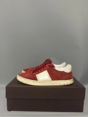 Valentino flycrews - Snygga sneakers från Valentino Garavani i rött och vitt med platt sula och rund tå. Ovandelen är i mocka och skinn, med röda snören och vita detaljer på sidorna och hälen. Ikoniska nitar på sulan ger extra edge till looken.