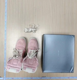 Rosa höga sneakers från Rick Owens - Unika höga sneakers från Rick Owens i ljusrosa och vitt. Skorna har pälsliknande yta, vita skinnpaneler och snörning framtill. Sidorna har grova dragkedjor och platt vit sula. Perfekt för dig som vill sticka ut med coola detaljer och exklusivt material.