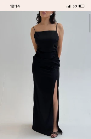 Svart lång satinklänning Bubbleroom - BUBBLEROOM OCCASION Tie Back Satin Gown Maxiklänning i satin från Bubbleroom Occasion - Öppen rygg - Snörningssystem för olika stilar - Sidoslits, Endast använd en gång, lite nött på snöret men inget man tänker på