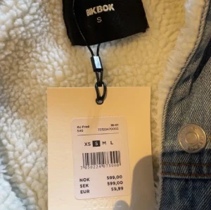 Ljusblå jeansjacka med teddyfoder Bik Bok - Säljer en snygg ljusblå jeansjacka från Bik Bok i storlek S. Jackan har ett mjukt vitt teddyfoder, klassiska silverfärgade knappar och två bröstfickor. Perfekt för dig som vill ha en chill och trendig look med extra värme.