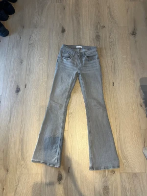 Grå bootcut jeans från Gina tricot strl 34 - Snygga grå jeans från Gina tricot i storlek 34. Modellen har bootcut-ben, klassisk femficksdesign och normal midja. Jeansen är tillverkade i mjukt denimtyg med lite stretch för skön passform. Perfekt för dig som gillar en stilren och avslappnad look.