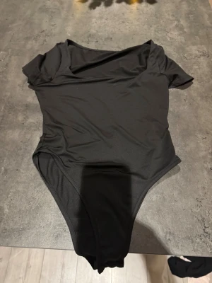 Svart kortärmad bodysuit - En stilren svart bodysuit med korta ärmar och rund halsringning. Tillverkad i ett stretchigt och mjukt material som sitter tight mot kroppen. Perfekt att styla med jeans eller kjol för en clean look.💞💞