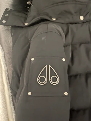 Svart Moose Knuckles dunjacka med päls - Säljer en svart dunjacka från Moose Knuckles med fluffig päls på huvan. Den är i storlek M men är liten i storleken så den passar S XS. Pris kan diskuteras 