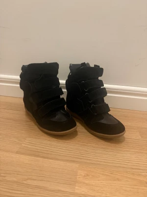 Svarta Isabel Marant sneakers med kardborre - Säljer ett par svarta höga sneakers från Isabel Marant med flera breda kardborreband och beige sula.  Skorna har en inbyggd klack vilket lägger till lite stil och höjd. Köpte dessa skor här på plick men de vart tyvärr lite för små, de är dock i suveränt skick!❤️