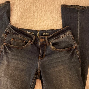 Bootcut jeans i mörkblå denim - Säljer ett par snygga bootcut jeans i mörkblå denim med klassiska fem fickor och kontrastsömmar. Lågmidjade och med snygga bakfickor. Lite stretch material i midjan. Även insydd av en skräddare i midjan vilket inte syns. Köpt i Brasilien. Skulle säga S/M. Har bara använt fåtal gånger.
