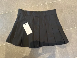 Svart plisserad minikjol från Zara - Säljer denna helt oanvända minikjol med shorts i i Zara!!