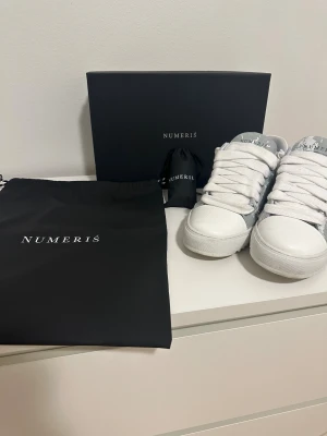 Numeris Cloud sneakers  - Säljer ett par Numeris Cloud i vitt/grått med den ikoniska paint-splash-designen. Storlek: 44  Skorna är endast använda ett fåtal gånger och är i nästan nyskick. Inga skador, inga fläckar – se bilder för skick.  Levereras komplett med: ✔ Originalbox ✔ Dustbag ✔ Extra snören ✔ Påse  Nypris ca 2 500 kr inklusive frakt. Mitt pris: 2 000 kr (Pris kan diskuteras vid snabb affär.)  Skorna kommer att rengöras noggrant innan frakt.