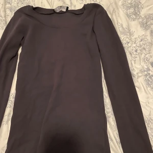 Svart  långärmad topp från Facy - Säljer en svart långärmad topp från Facy med rund halsringning. Modellen är ribbad och har en tight passform som sitter snyggt på kroppen. Perfekt att styla med jeans eller kjol för en clean look.